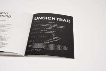 Aufgeschlagenes Zine mit der Beschreibung der unsichtbar in lateinischer Schrift und Braille
